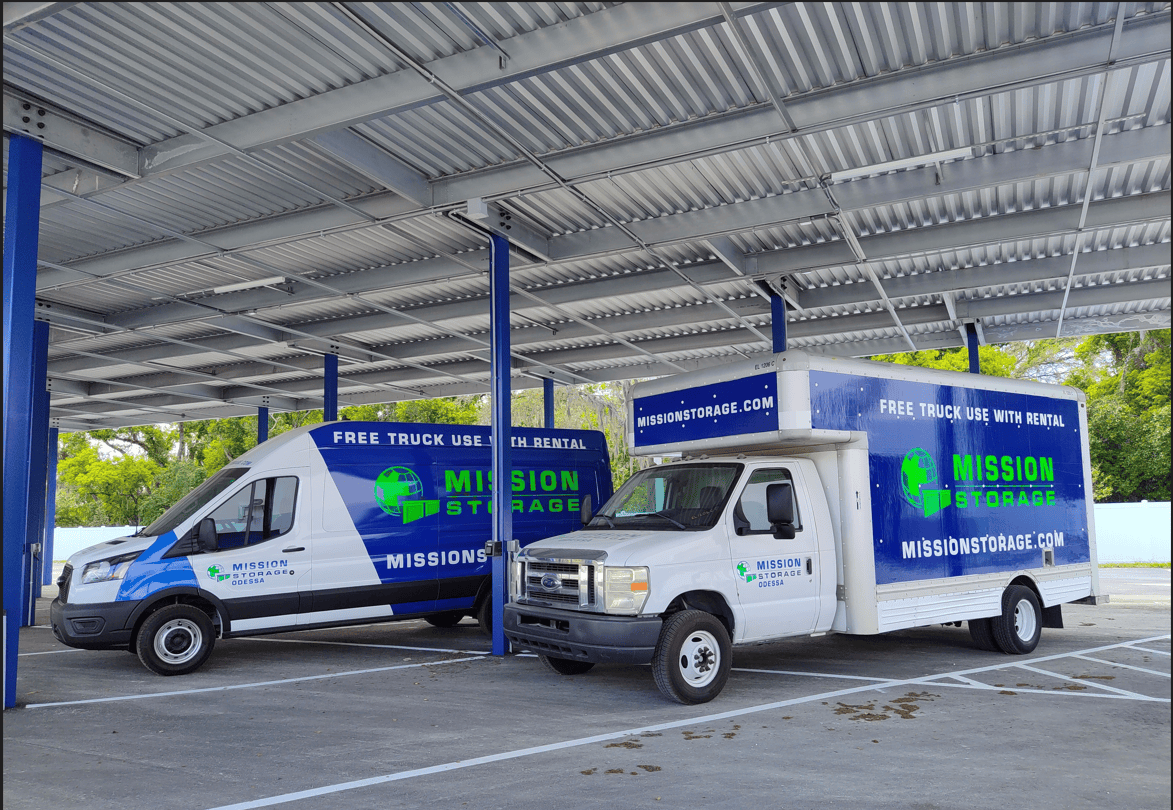 Moving vans with Mission Storage Branding parked underneath the covered vehicle storage area